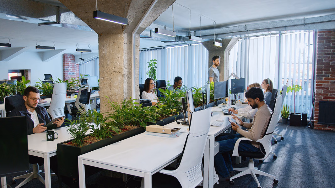 IT professionals working in a modern office environment using managed desktop and mobile devices.