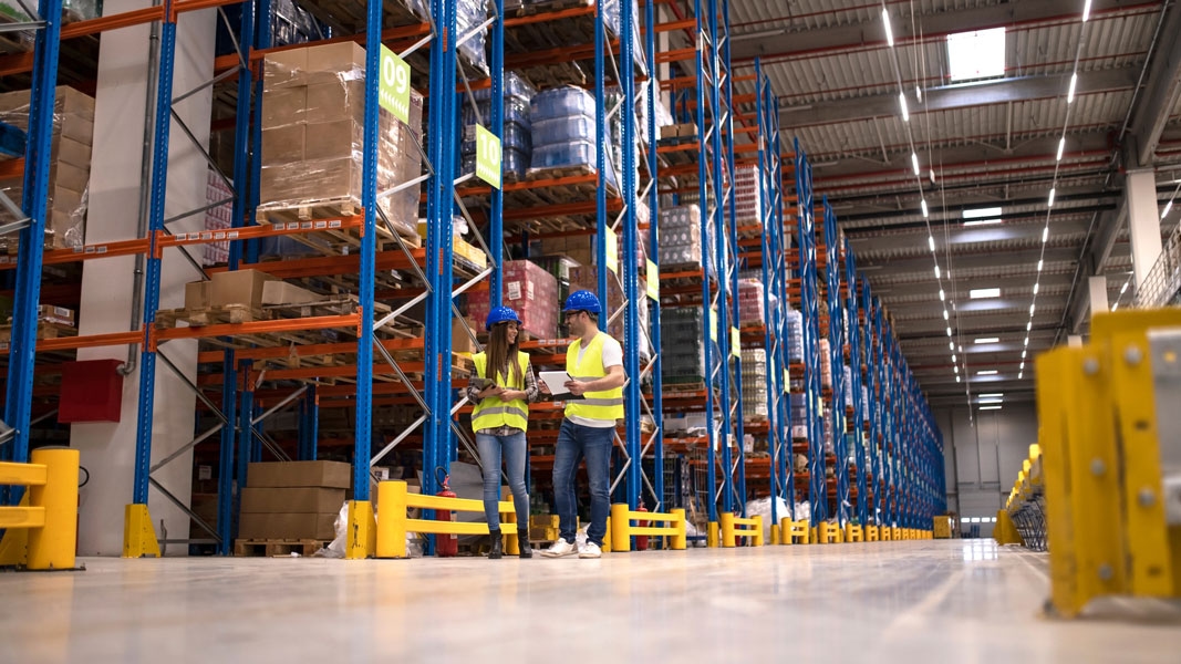 Warehouse workers checking inventory with rugged mobile devices in a logistics facility.
