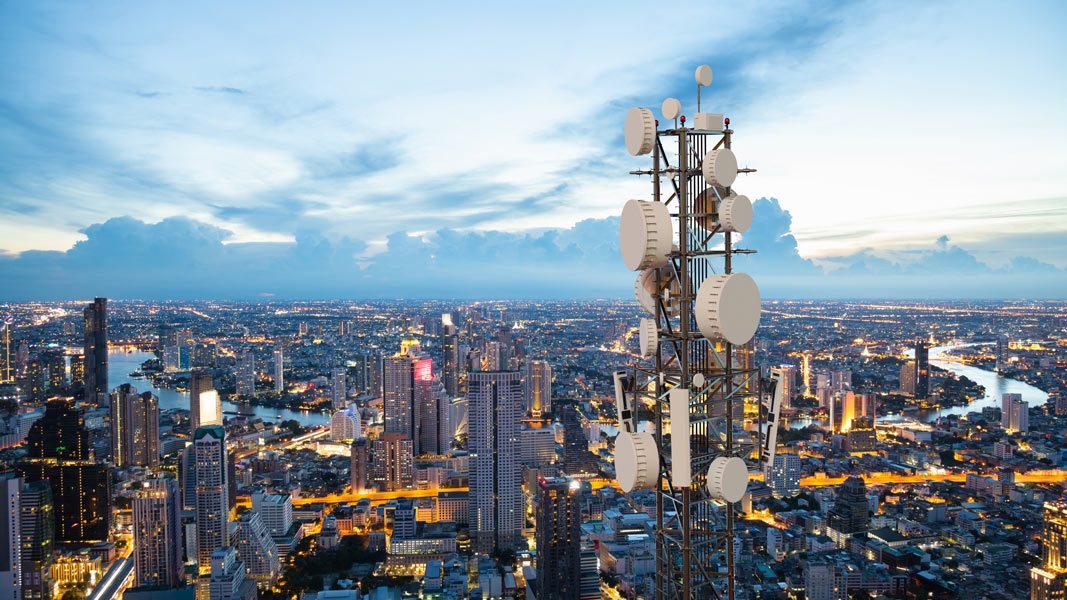 Telecommunications cell tower overlooking a city, representing wide-scale network and device security.